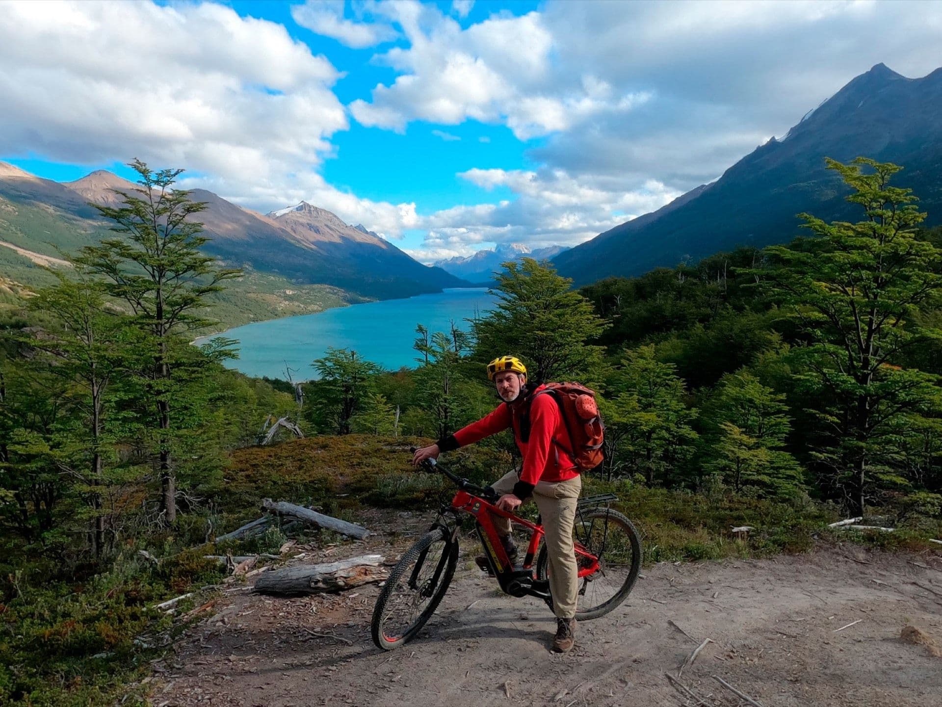 Ciclista con bicicleta cargada, en un mirador con vista al Lago del Desierto y el cerro Fitz Roy