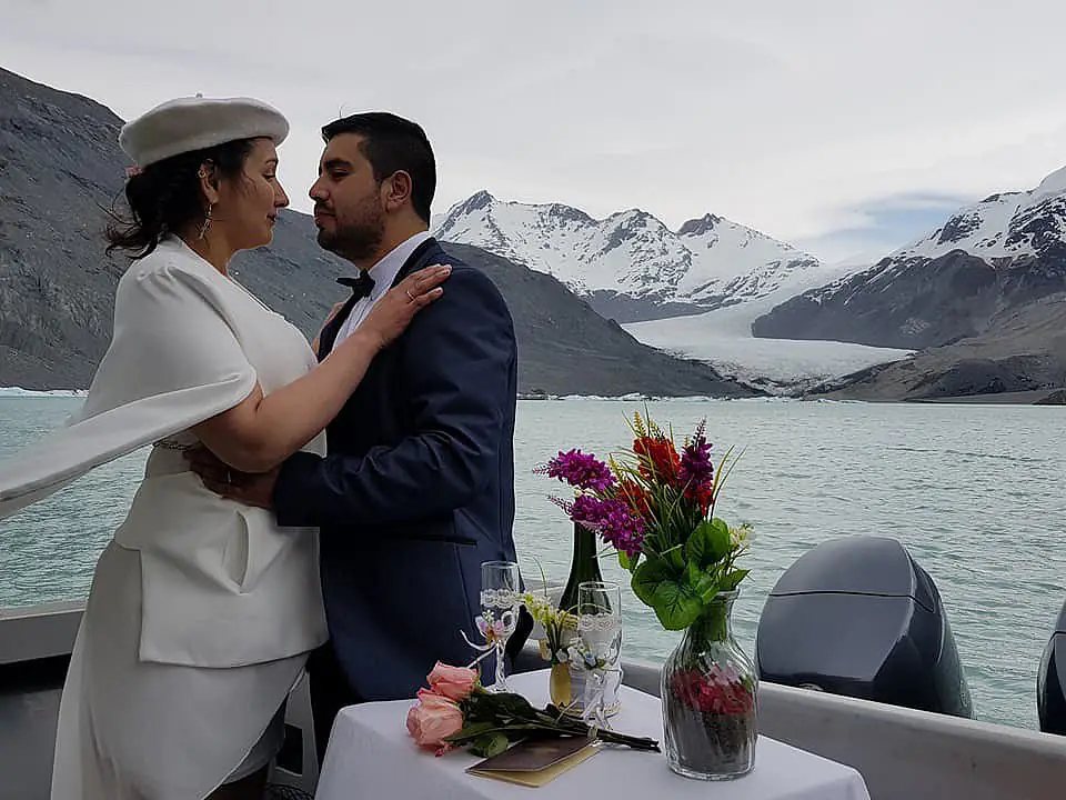 Mariana y Jonathan abrazados a bordo, con el Glaciar O'Higgins de fondo