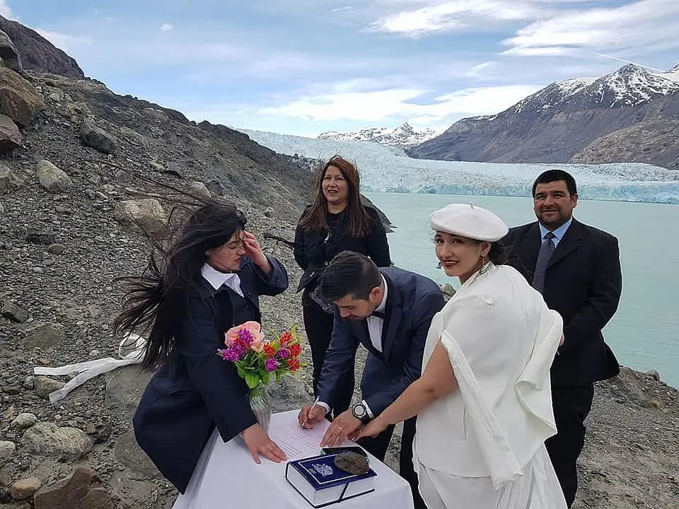Mariana y Jonathan firmando la libreta de matrimonio, con el Glaciar O'Higgins de testigo