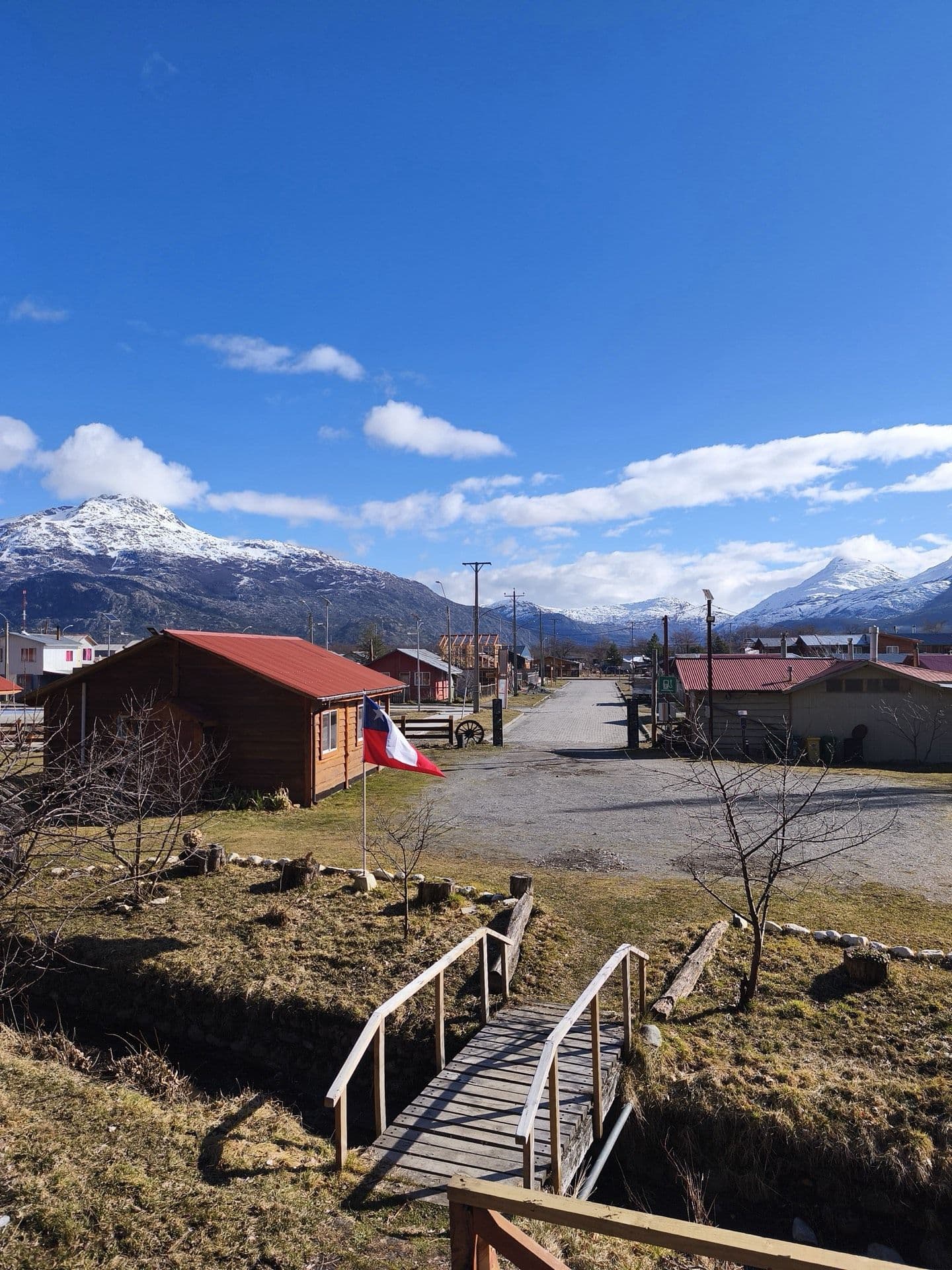 La calle principal de Villa O'Higgins, con las montañas nevadas al fondo